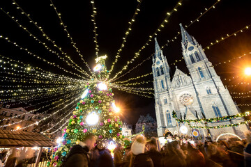 famous Christmas winter holiday markets on the Náměstí míru (Peace square) in the centre of Prague, festive season decoration with tree and light chains 