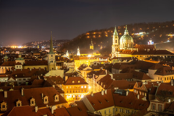 winter view from the Prague Castle to the Saint Nicholas church on Malá Strana in the historical center of Prague. Park on the Petřín hill in the background. typical red rooftops in the foreground 