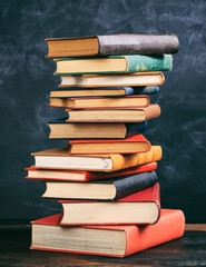 Vintage books stack on black board background, vertical