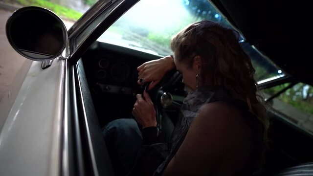 unhappy lonely woman is crying inside car, leaning on steering wheel, abandoned