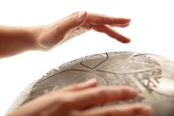 A close up of hands playing the hank drum on white studio background. Concept of hobby, professional occupation, music, traditions, festival. Copyspace for your ad. Ethnic instrument.
