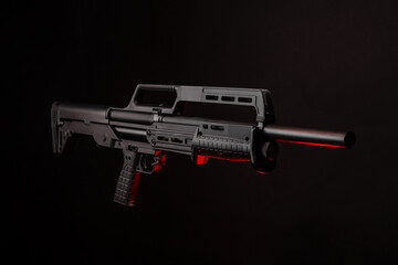 Modern tactical pump action shotgun on a dark back. Red backlight.