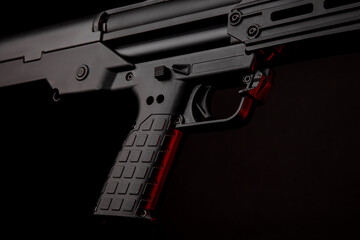 Close up of a modern tactical pump action shotgun against a dark back. Red backlight.