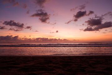 A dramatic sunset view on Kuta beach, Bali, with gradations of purple, orange and blue sky
