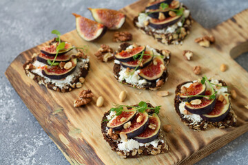 Fototapeta na wymiar Toast with figs, honey, cheese and nuts on rustic wooden board