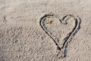 High angle view of a starfish in a heart drawn in sand