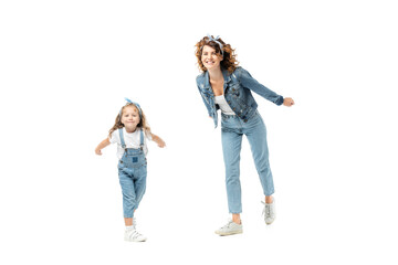 Fototapeta premium mother and daughter in denim outfits posing and smiling isolated on white