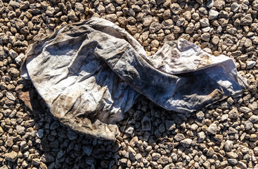 Dirty old wrinkled cloth on gravel
