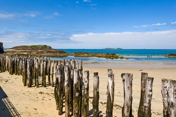 Wooden Poles on the beach at low tide in Saint Malo, Brittany, France - obrazy, fototapety, plakaty