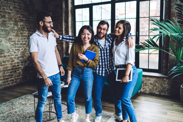 Group of laughing multiethnic coworkers hugging in office