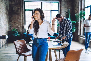 Smiling woman having conversation on cellphone in office