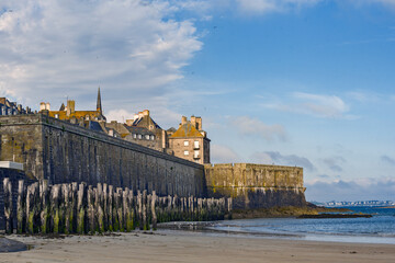 Fototapeta na wymiar rampart and wooden poles on the beach at low tide in Saint Malo, Brittany, France