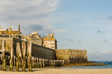 rampart and wooden poles on the beach at low tide in Saint Malo, Brittany, France
