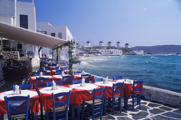 Empty chairs with tables in a restaurant by the sea 