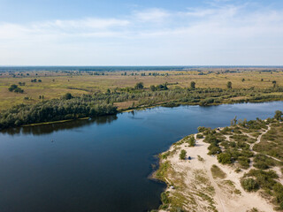 Aerial drone view. The bend of a wide river among green meadows. Sunny summer day.