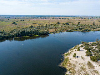 Aerial drone view. The bend of a wide river among green meadows. Sunny summer day.