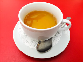 A tea cup with a spoon on a red