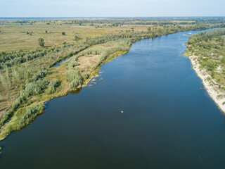 Aerial drone view. The bend of a wide river among green meadows. Sunny summer day.