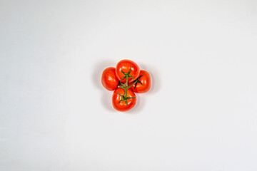 Red tomatoes on a branch on a white background, top view