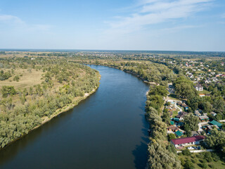 Aerial drone view. The bend of a wide river among green meadows. Sunny summer day.