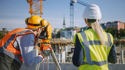 Construction Worker Using Theodolite Surveying Optical Instrument for Measuring Angles in...