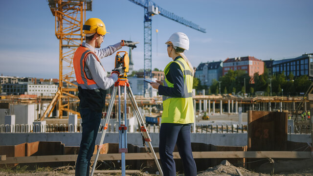 Construction Worker Using Theodolite Surveying Optical Instrument for Measuring Angles in Horizontal and Vertical Planes on Construction Site. Engineer and Architect Using Tablet Next to Surveyor.