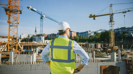 Confident Bearded Head Civil Engineer-Architect in Sunglasses is Standing Outside with His Back to...