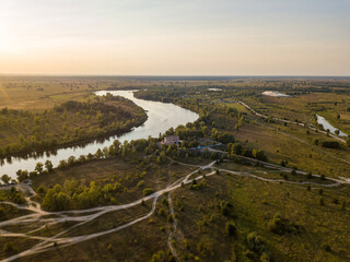 Fototapeta na wymiar Aerial drone view. The bend of a wide river among green meadows. Sunny summer day.