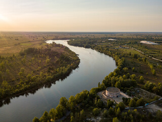 Fototapeta premium Aerial drone view. The bend of a wide river among green meadows. Sunny summer day.