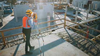 Construction Worker Using Theodolite Surveying Optical Instrument for Measuring Angles in...