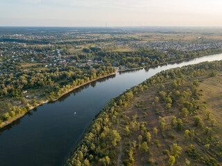 Fototapeta premium Aerial drone view. The bend of a wide river among green meadows. Sunny summer day.