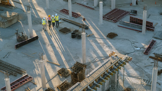 Aerial Shot of a New Constructions Development Site with Diverse team of Engineers and Architects Discussing Real Estate Projects. Heavy Machinery and Construction Workers are Working in the Area.