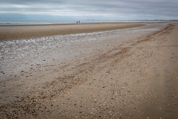 Lone walkers on a deserted beach at Dymchurch, Kent, England