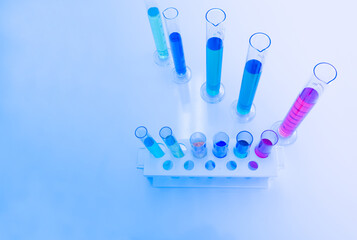 The test tube has a multicolored liquid inside. Put on a table for science experiments, color tones.