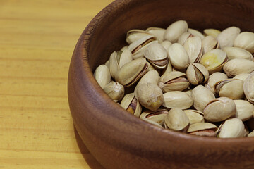 Dry roasted Pistachios in wooden bowl with copy space