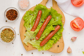 Vegetarian meat concept. Sausages on lettuce leaves. White background. View from above