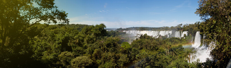 Large nature panorama of Iguacu (Iguazu) waterfall cascade on border of Brazil and Argentina. Amazing view of falls Cataratas in bright Sunny weather. Concept of travel. Copyright space for site