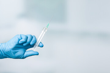 Close up of doctor's hand in medical gloves holding a syringe with serum 