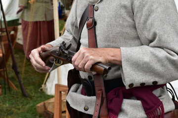 A man demonstrates a flintlock pistol at an autumn festival.