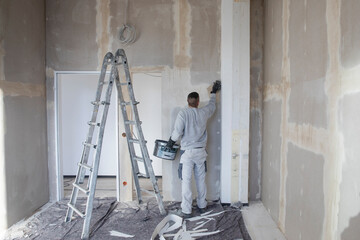 Handwerker glättet die Wände auf einer Baustelle - obrazy, fototapety, plakaty