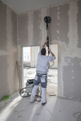 Handwerker schleift die Wände auf einer Baustelle