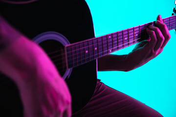 Obraz na płótnie Canvas Close up of guitarist hand playing guitar, macro. Concept of advertising, hobby, music, festival, entertainment. Person improvising inspired. Copyspace to insert image or text. Colorful neon lighted.