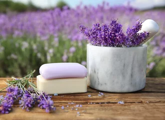 Rolgordijnen Fresh lavender flowers, soap bars and white marble mortar on wooden table outdoors, closeup © New Africa