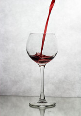 In a wine glass, standing on a white background, wine is poured from above