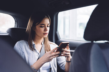 Fototapeta na wymiar Pensive young woman using smartphone in car