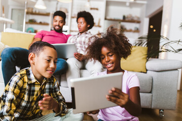 Family at home.African american boy and girl lying on floor and using digital tablet.