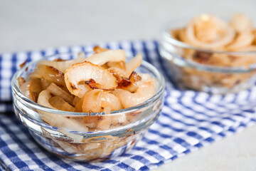 Tasty fried onion in glass bowl on table, closeup