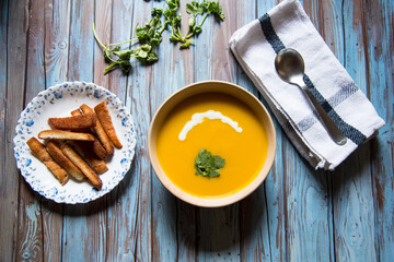 Pumpkin and cream soup with bread crumbs with condiments on a background