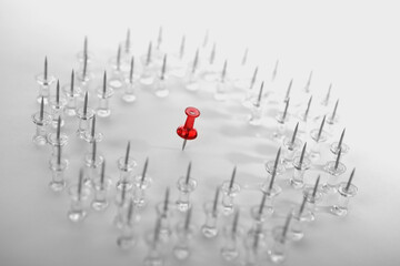 Close-up of red thumbtack surrounded by white thumbtacks in a circle