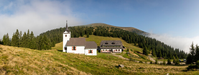 panorama view mountain range Gleinalm or Gleinalpe with summit Speikkogel and mountain hut named Gleinalmschutzhaus and chapel in the Austrian federal state of Styria